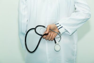 Midsection of female doctor holding stethoscope while standing in hospital