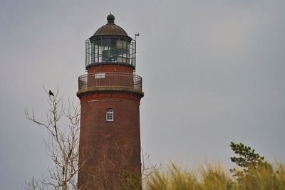 Low angle view of lighthouse by building against sky