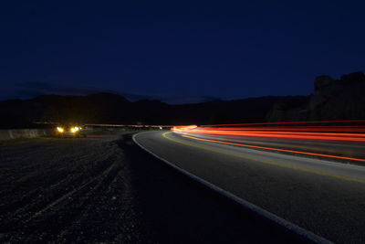 Light trails on road against sky at night