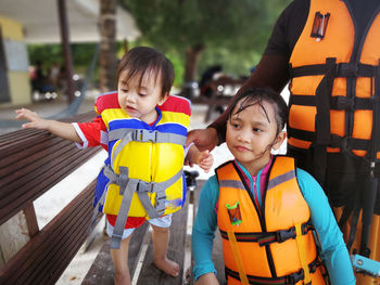 Girl standing with father and baby girl at beach