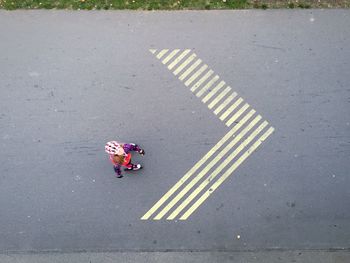 High angle view of girl roller skating by arrow symbol on road