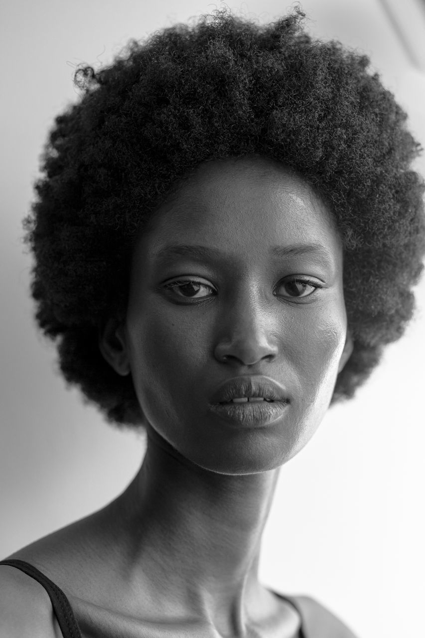 human hair, portrait, hairstyle, afro, black and white, one person, headshot, curly hair, adult, young adult, black, women, studio shot, human face, monochrome, monochrome photography, indoors, looking at camera, fashion, serious, close-up, front view, short hair, human head, individuality, female, long hair, clothing, white, looking, lifestyles, nose