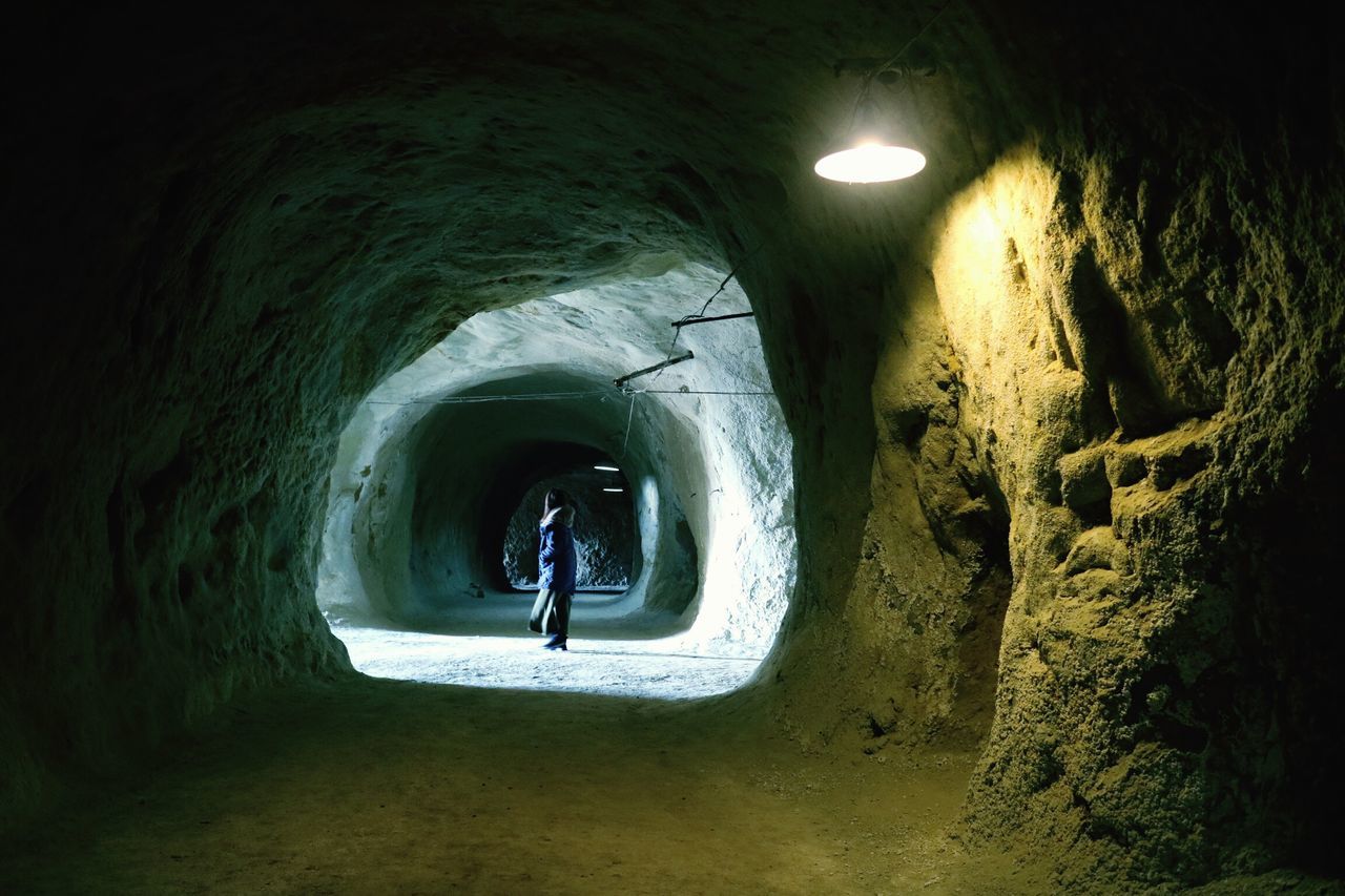 tunnel, indoors, arch, built structure, architecture, illuminated, lighting equipment, wall - building feature, the way forward, night, circle, hole, walking, archway, wall, light at the end of the tunnel, full length, unrecognizable person