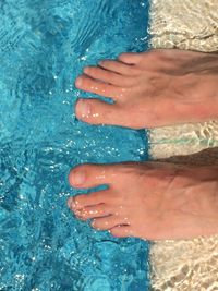 Low section of woman standing in swimming pool