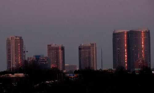 Illuminated buildings in city against sky