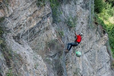 Climber placing safety nets to avoid falling rocks