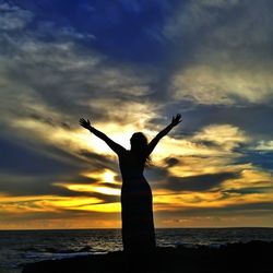 Silhouette of man standing on beach at sunset