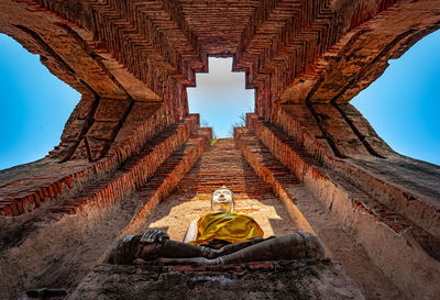 Man sitting in temple against sky