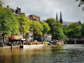 Sailboats moored on river by buildings in city against sky