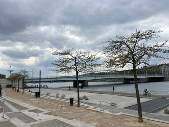 Footpath by street in city against sky