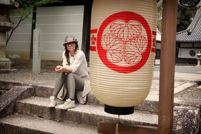 Portrait of young woman sitting on steps outside temple