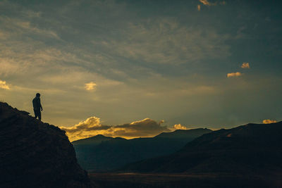 Silhouette person standing on mountain against sky during sunset