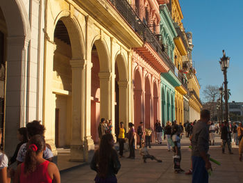 People on sidewalk against historic building in city