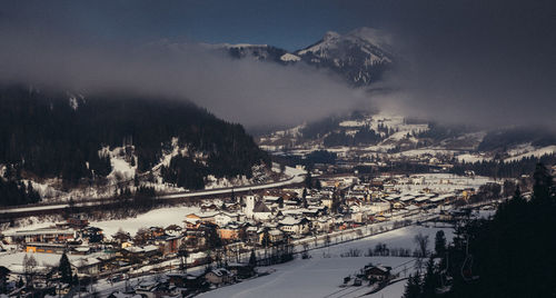 High angle view of snowcapped mountains against sky and small villeage town