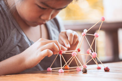 Cute girl making molecule model on wooden table in porch