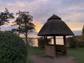 Gazebo by trees against sky during sunset