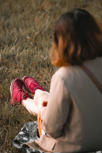 Rear view of woman sitting on field