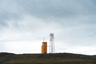 Lighthouse on street amidst buildings against sky