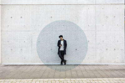 Full length of a young man standing on wall