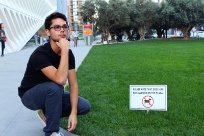 Man crouching by signboard in park