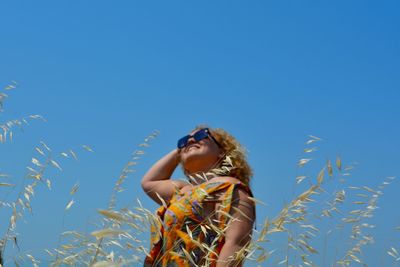 Low angle view of woman standing against blue sky