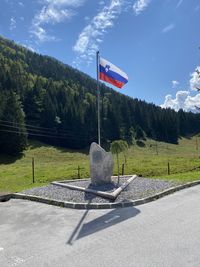 Information sign on road by trees against sky