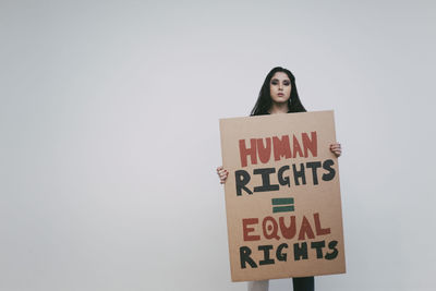 Female activist with human rights signboard against white wall