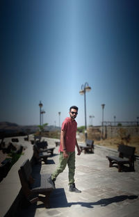 Portrait of man standing on footpath against sky