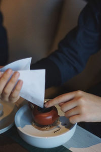 Midsection of woman holding paper with tea leaves at table