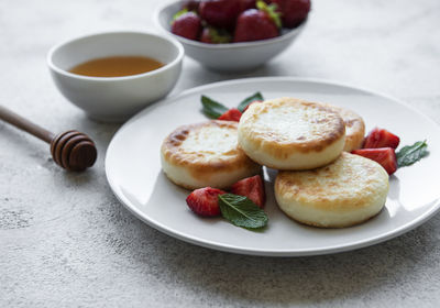 Cottage cheese pancakes, ricotta fritters on ceramic plate with fresh strawberry. 