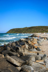 Rocks on beach against clear blue sky