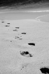 Footprints on sand at beach against sky