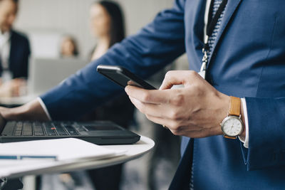 Midsection of man using smart phone on table