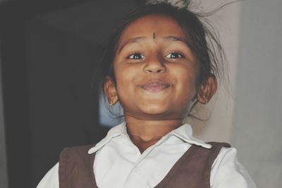 Portrait of smiling girl standing against wall