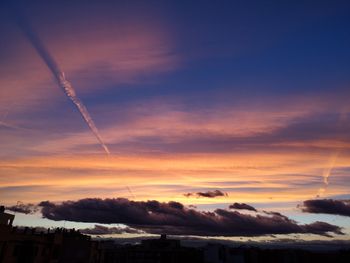 Low angle view of vapor trails in sky during sunset