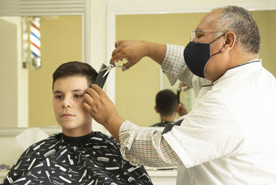 View of barber cutting hair of boy at barber shop