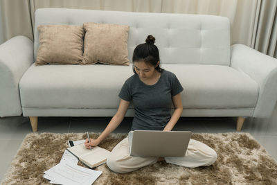 Young man using mobile phone while sitting on sofa at home