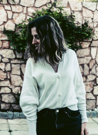 Full length of young woman standing against brick wall