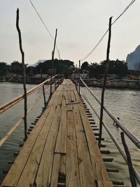 Boats moored on jetty by river against sky