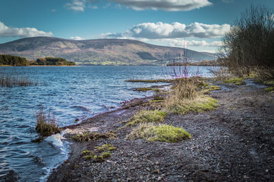 Scenic view of river by mountain against sky