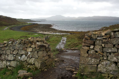 Scenic view of stone wall by mountain against sky