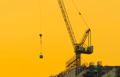 Crane at construction site against sky during sunset