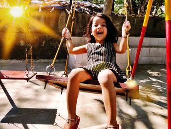 Portrait of a smiling young woman sitting on swing