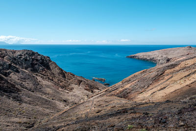 Scenic view of sea and mountains against blue sky