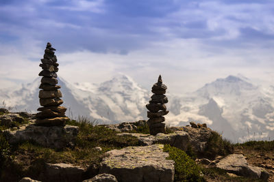 Stack of rocks on mountains against cloudy sky during sunny day