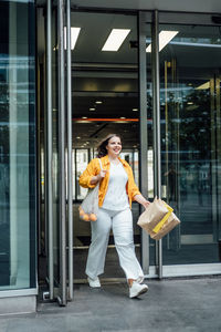 Happy confident smiling plus size curvy young woman with shopping bags walking on city street near