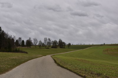 Road amidst field against sky