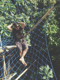 Mid adult man sitting on net at forest