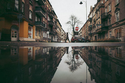 Reflection of buildings in puddle on street