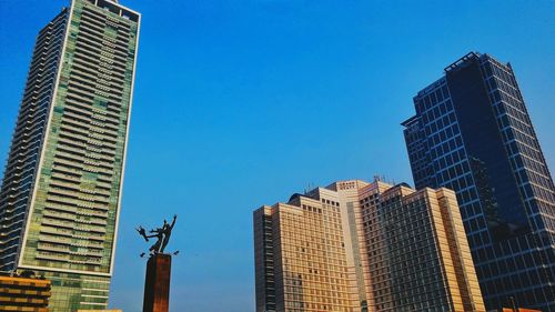 Low angle view of modern buildings against clear blue sky